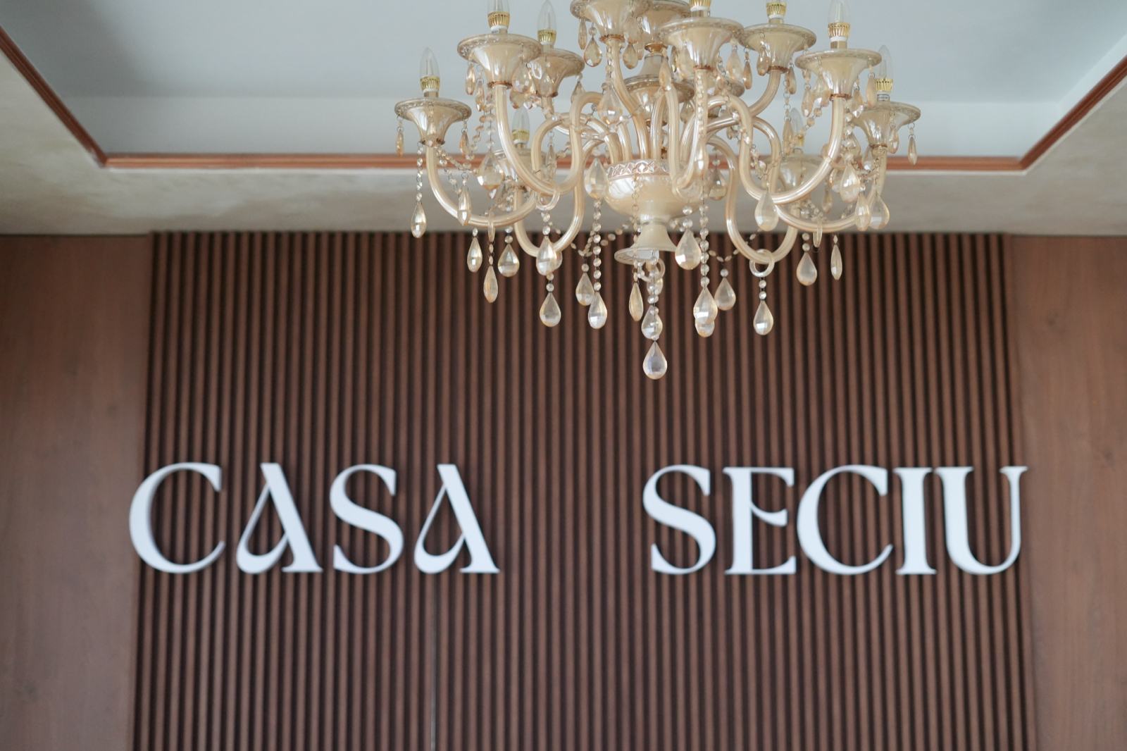 Perete cu literele Casa Seciu și candelabru, într-o sală de evenimente