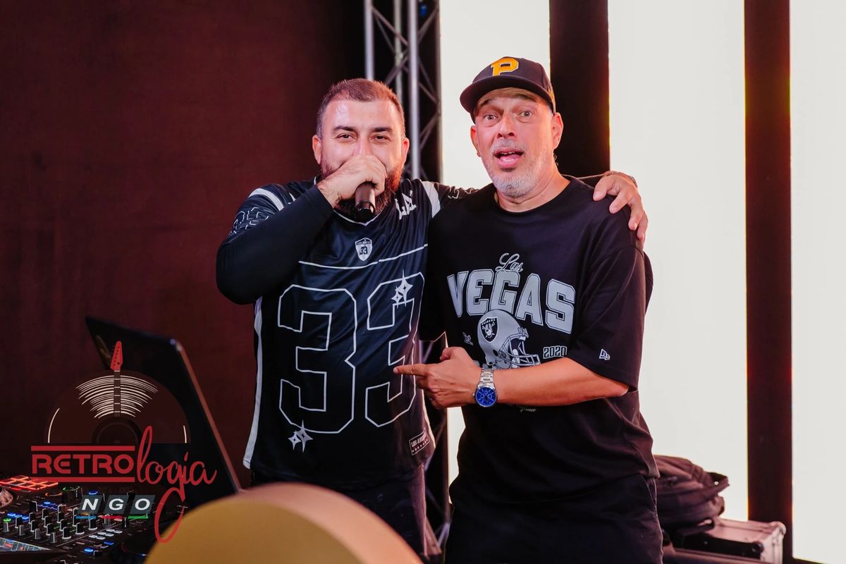 DJ Papee și DJ iuLio pe scenă, lângă pupitru, unul cu microfonul în mână, celălalt cu șapcă