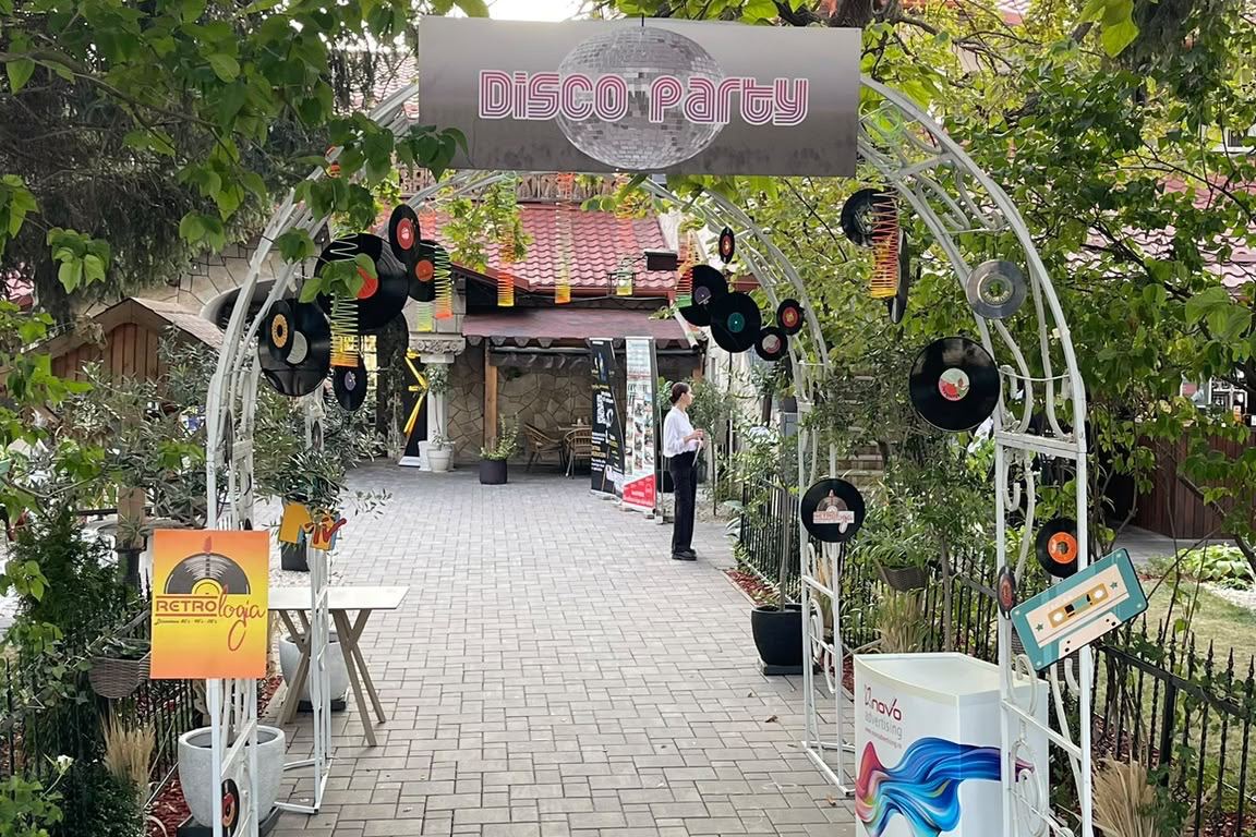 Intrarea la Casa Seciu, sub o arcadă cu discuri de vinil și casete audio, cu firma „Disco Party” și glob disco deasupra aleii